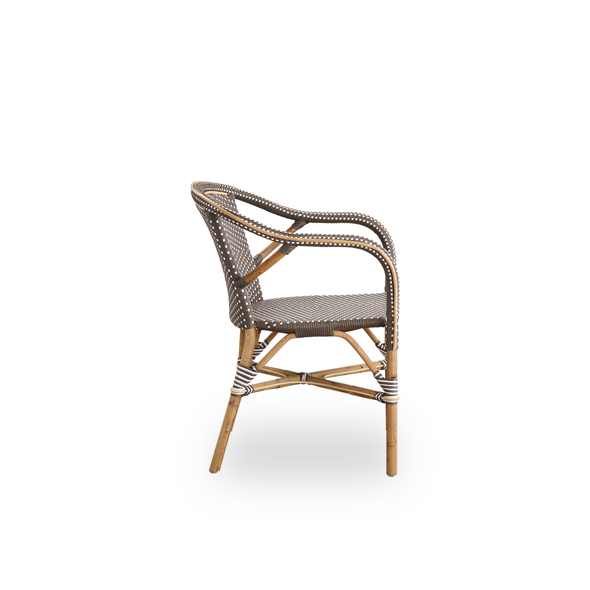 Seitenansicht des Madeleine Essstuhls mit Armlehnen. Rattanrahmen mit Sitz und Rückenlehne aus braunem ArtFibre mit weißen Punkten. Inspiriert vom Bistro-Design der 1950er Jahre.