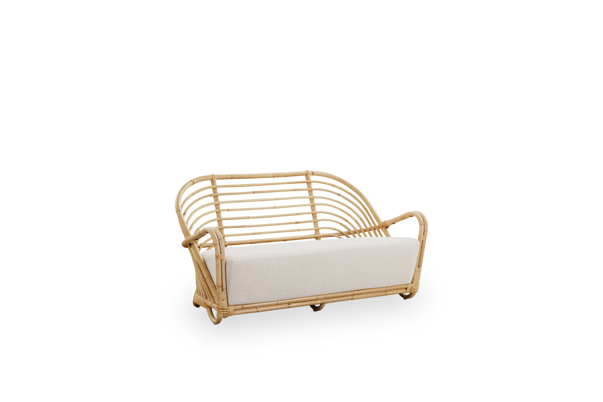 Seitenansicht des Charlottenborg 2-Sitzer-Sofas aus poliertem Natur-Rattan, entworfen von Arne Jacobsen. Das Sofa verfügt über eine gebogene Rückenlehne und in die Basis integrierte Armlehnen, handgefertigt aus hochwertigem indonesischem Rattan.
