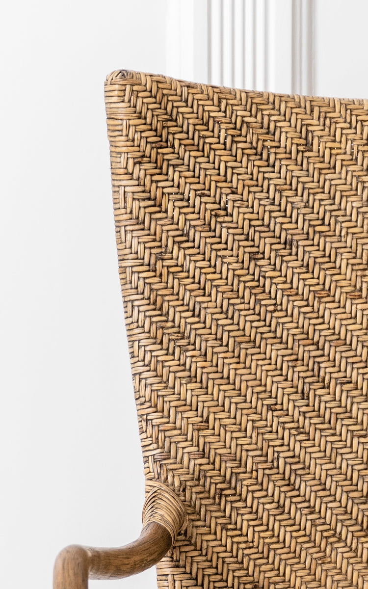 Dies ist ein Nahaufnahmebild von Melody Dining Armchair i antique rattan. Detail der Fischgrätgeflecht-Rückenlehne und der gebogenen Rattan-Armlehne.