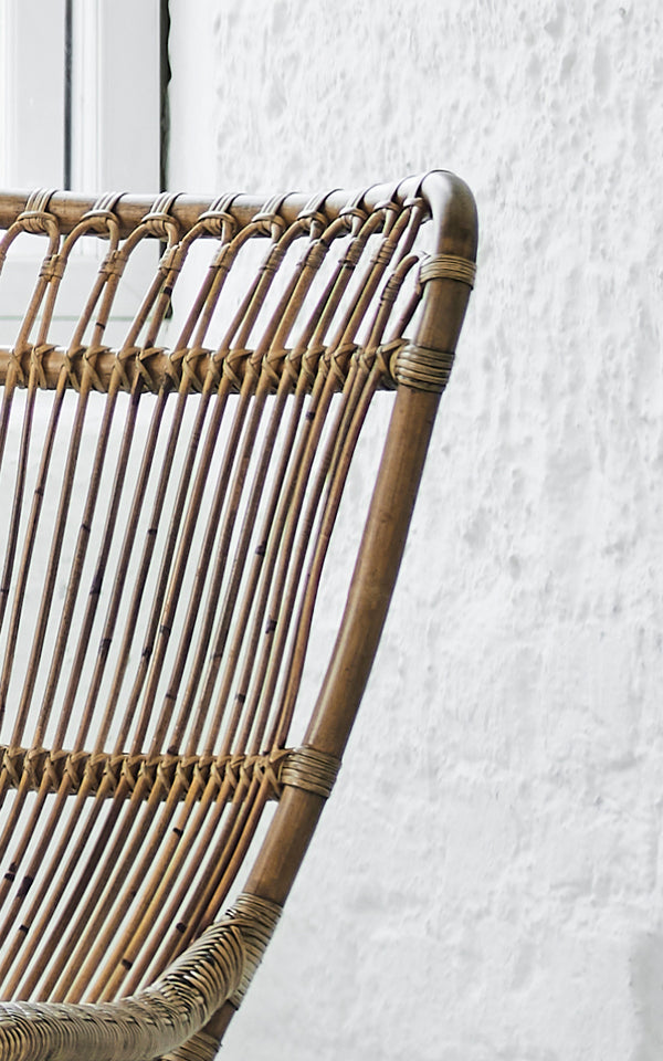 Dies ist ein Nahaufnahmebild von Monet Lounge Chair i antique rattan. Detail der Schlaufenbogen-Rückenlehne mit vertikalen Stäben und geflochtenem Sitz.