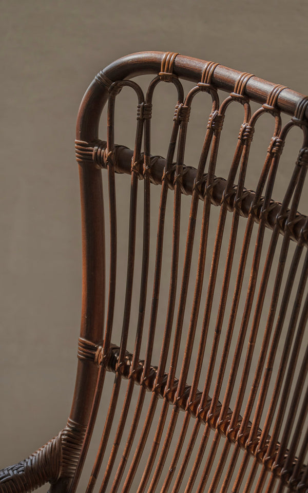Dies ist ein Nahaufnahmebild von Monet Lounge-Sessel in brown rattan. Rückenlehne mit Bögen und senkrechten Rattanstreben.