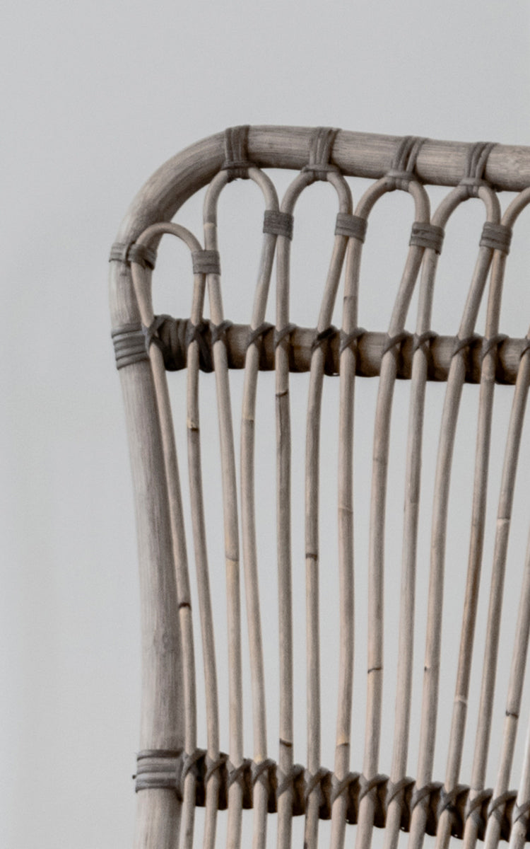 Dies ist ein Nahaufnahmebild von Monet Lounge Chair i taupe rattan. Detail des Schlaufenbogen-Designs und der vertikalen Stäbe in warmem Taupe-Ton.
