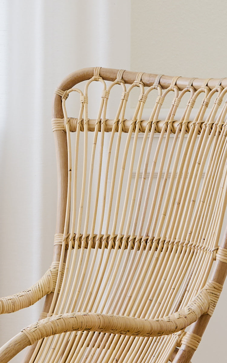 Dies ist ein Nahaufnahmebild von Monet Lounge Chair i natural rattan. Detail der Schlaufenbögen und der glatten vertikalen Rattanstäbe.