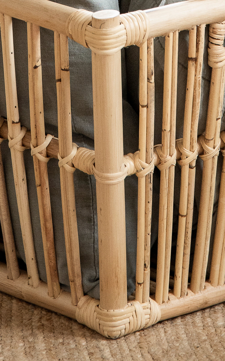 Dies ist ein Nahaufnahmebild von Marche Korb in natural rattan. Vertikale Rattanstäbe mit umwickelten Verbindungen und offener Lattenkonstruktion.