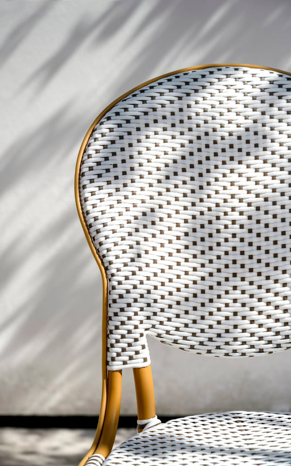 Dies ist ein Nahaufnahmebild von Isabell Außen-Esszimmerstuhl in almond aluminium frame white w cappuccino dot artfibre. Ovale geflochtene Rückenlehne im Sonnenlicht.