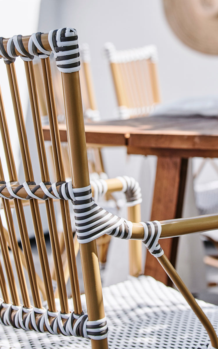 Dies ist ein Nahaufnahmebild von Monique Exterior Dining Armchair i white w cappuccino dot ArtFibre. Detail des Punktgeflechts und der Armlehne.