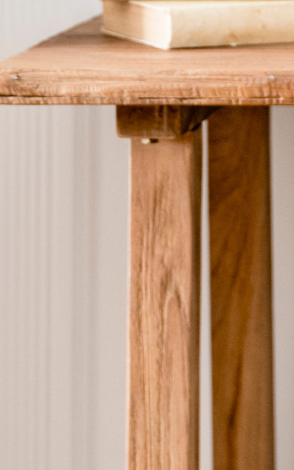 Dies ist ein Nahaufnahmebild von Lucas Teak Schreibtisch in teak indoor. Die Kante der Teakoberfläche und die gewinkelten Beine zeigen die warme Maserung und stabile Bauweise.