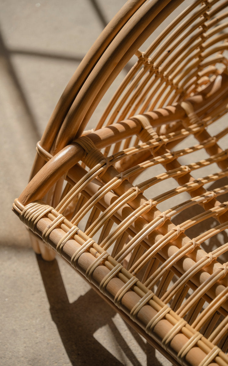 Dies ist ein Nahaufnahmebild von Paris Lounge-Sessel in polished natural rattan. Rattan-Sitzrahmen und umwickelte Details im Sonnenlicht.