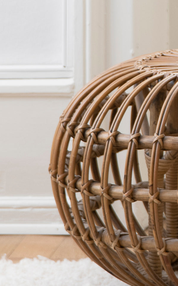 Dies ist ein Nahaufnahmebild von Ottoman Small in polished antique rattan. Detail der offenen Rattan-Käfigstruktur mit Kreuzbindungen.
