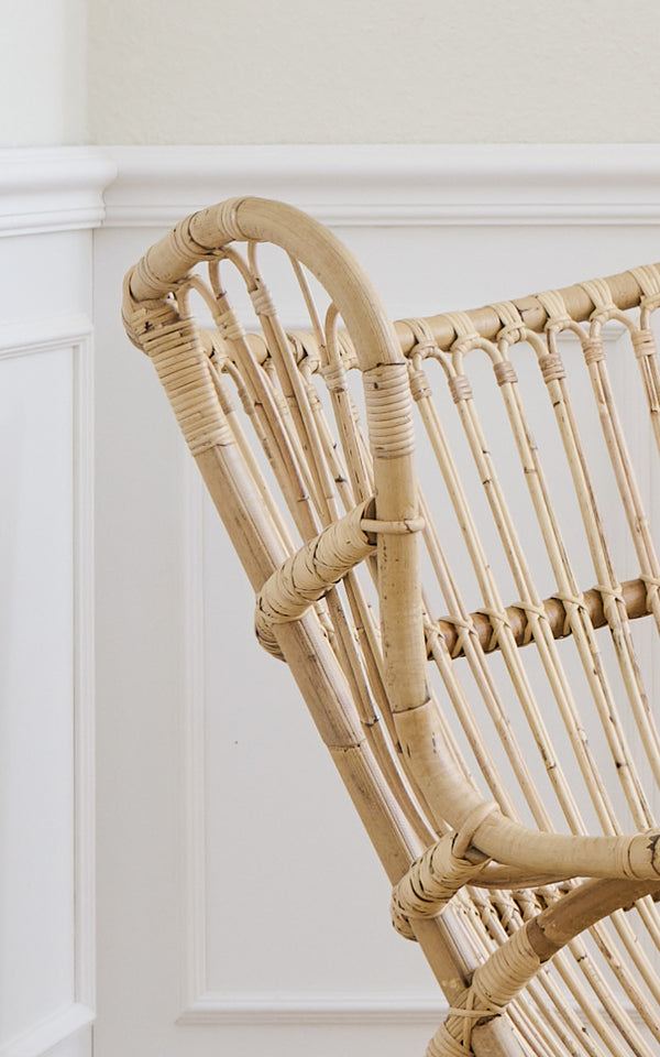 Dies ist ein Nahaufnahmebild von Teddy Lounge-Sessel in polished natural rattan. Detail der geschwungenen Rattan-Oberleiste und Sprossenrückenlehne.