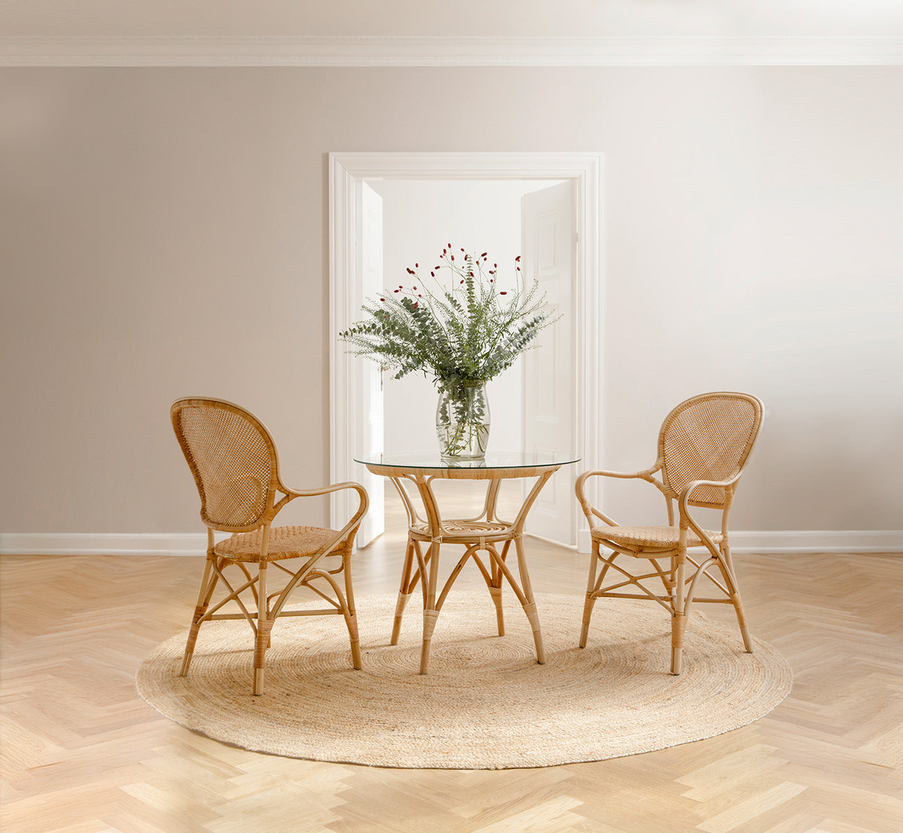 Dies ist ein Lifestyle-Bild von Rossini Dining Armchair in natural rattan. In einem hellen Interieur gestylt.