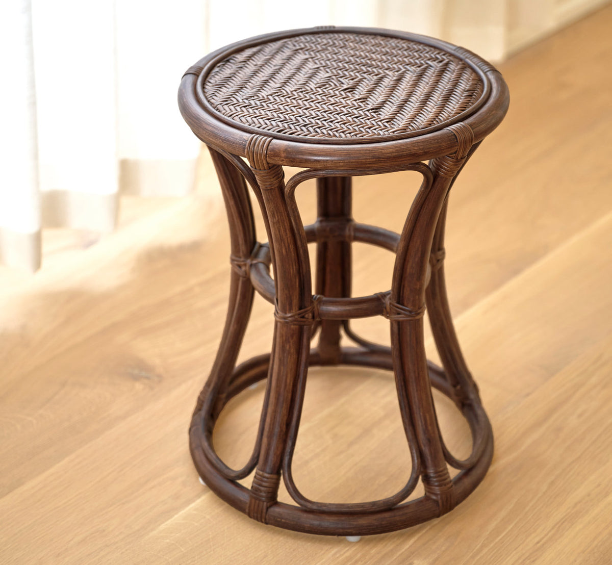 Dies ist ein Lifestyle-Bild von Bella Hocker in brown rattan. Allein auf einem warmen Eichenboden.