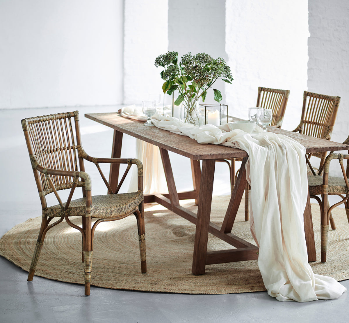 Dies ist ein Lifestyle-Bild von Piano Esszimmerstuhl in antique rattan. Um einen rustikalen Holzesstisch mit Leinenläufer und Kerzen.