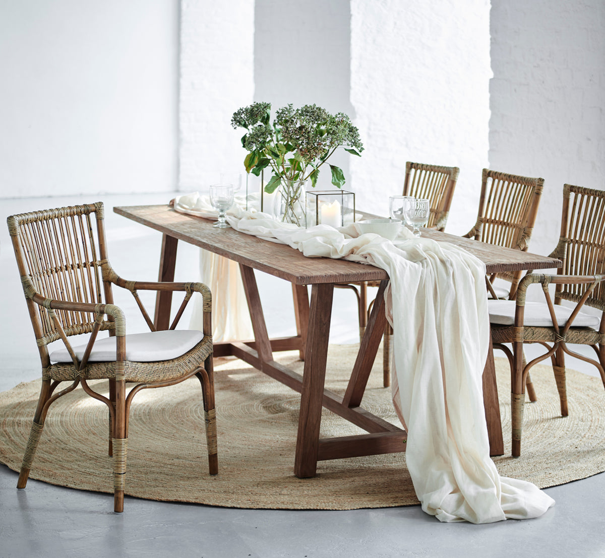 Dies ist ein Lifestyle-Bild von Piano Esszimmerstuhl in antique rattan. Um einen rustikalen Holzesstisch mit Leinenläufer und Kerzen.