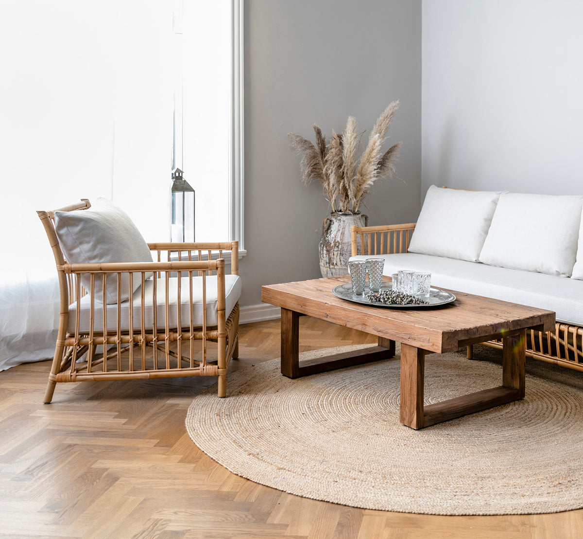 Dies ist ein Lifestyle-Bild von Caroline Lounge-Sessel in natural rattan, in einem hellen skandinavischen Wohnzimmer mit Fischgrätparkett.