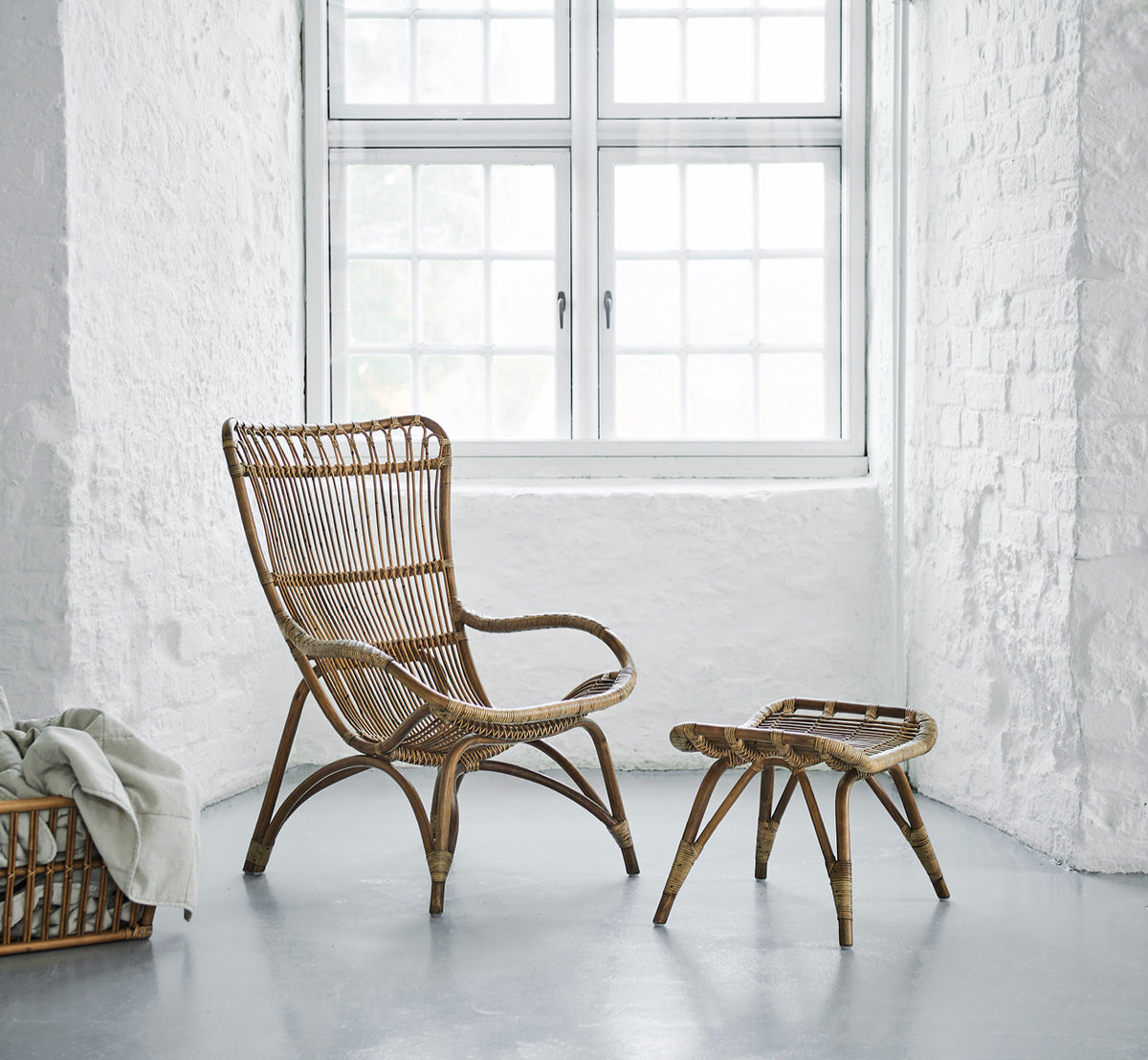 Dies ist ein Lifestyle-Bild von Monet Lounge Chair i antique rattan. In einem Raum mit Schmetterlings-Tapete und dekorativen marokkanischen Laternen.
