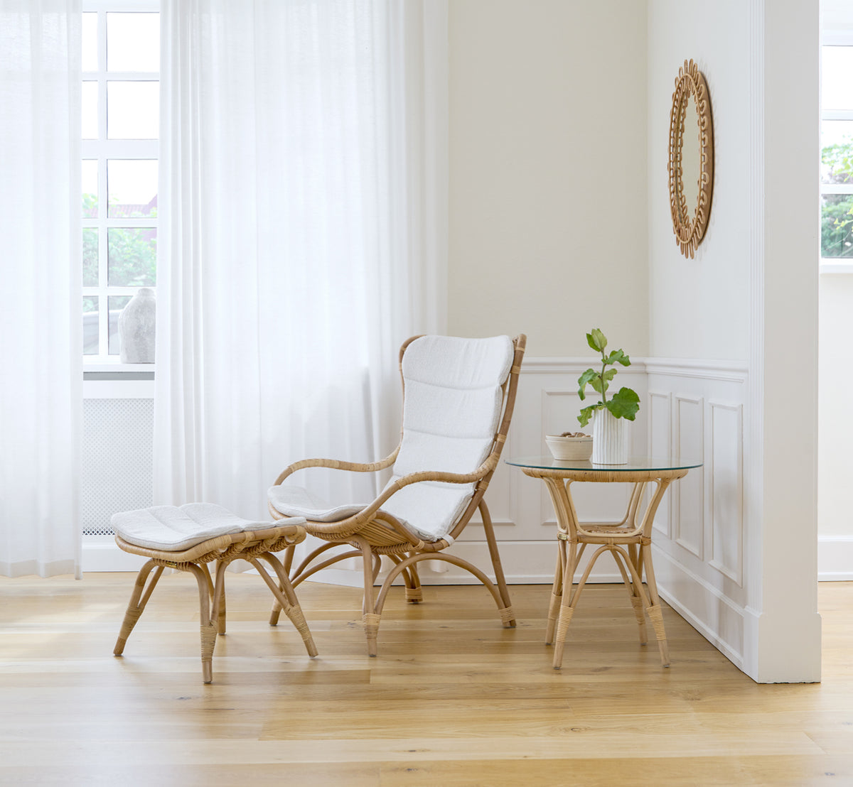 Dies ist ein Lifestyle-Bild von Monet Lounge Chair i natural rattan. In einem Raum mit rosafarbenen Wänden, Fischgrätboden und Rattan-Servierwagen.