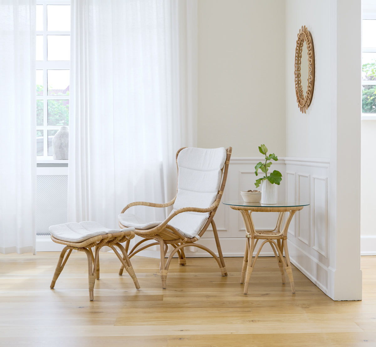 Dies ist ein Lifestyle-Bild von Monet Footstool i natural rattan. Mit Lounge-Sessel und Beistelltisch in einem hellen getäfelten Raum.