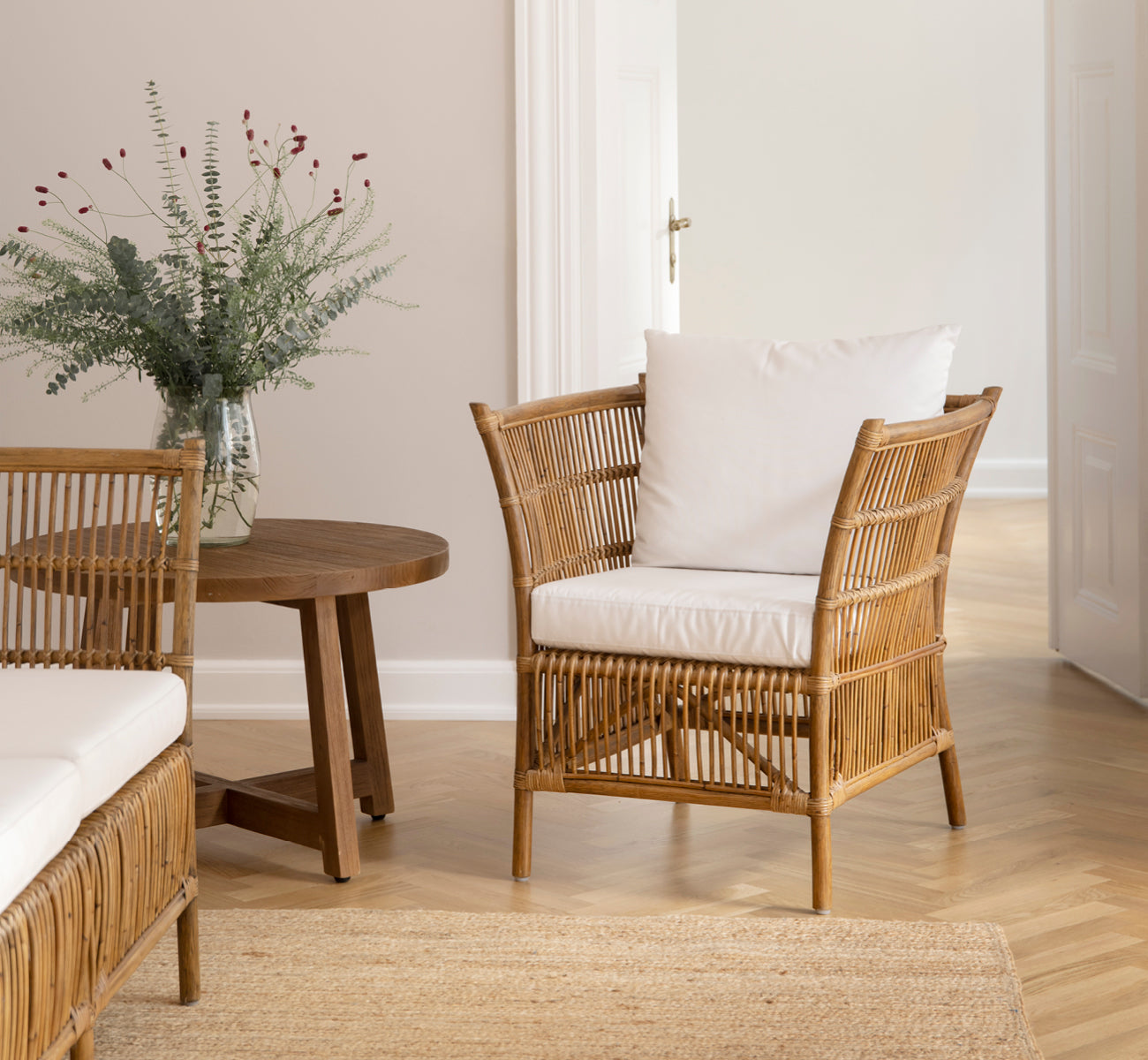 Dies ist ein Lifestyle-Bild von Donatello Lounge-Sessel in antique rattan, in einem hellen Wohnzimmer mit Fischgrätparkett und üppigem Grün.