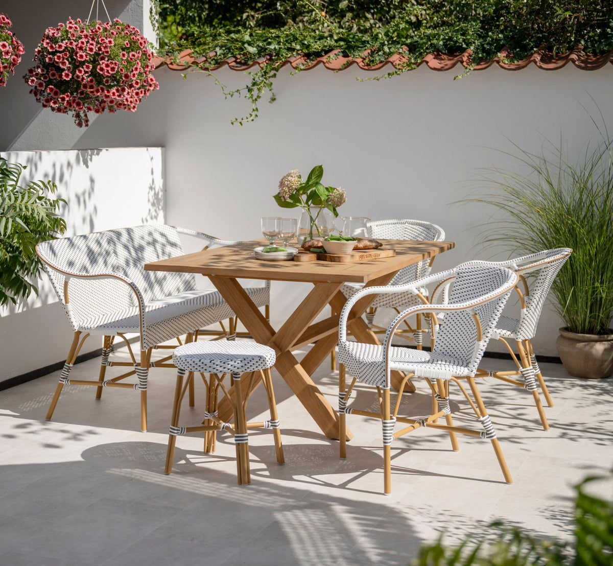 Dies ist ein Lifestyle-Bild von Simone Außenhocker in almond aluminium frame white w cappuccino dot artfibre. Mit Teaktisch auf einer sonnigen Terrasse.