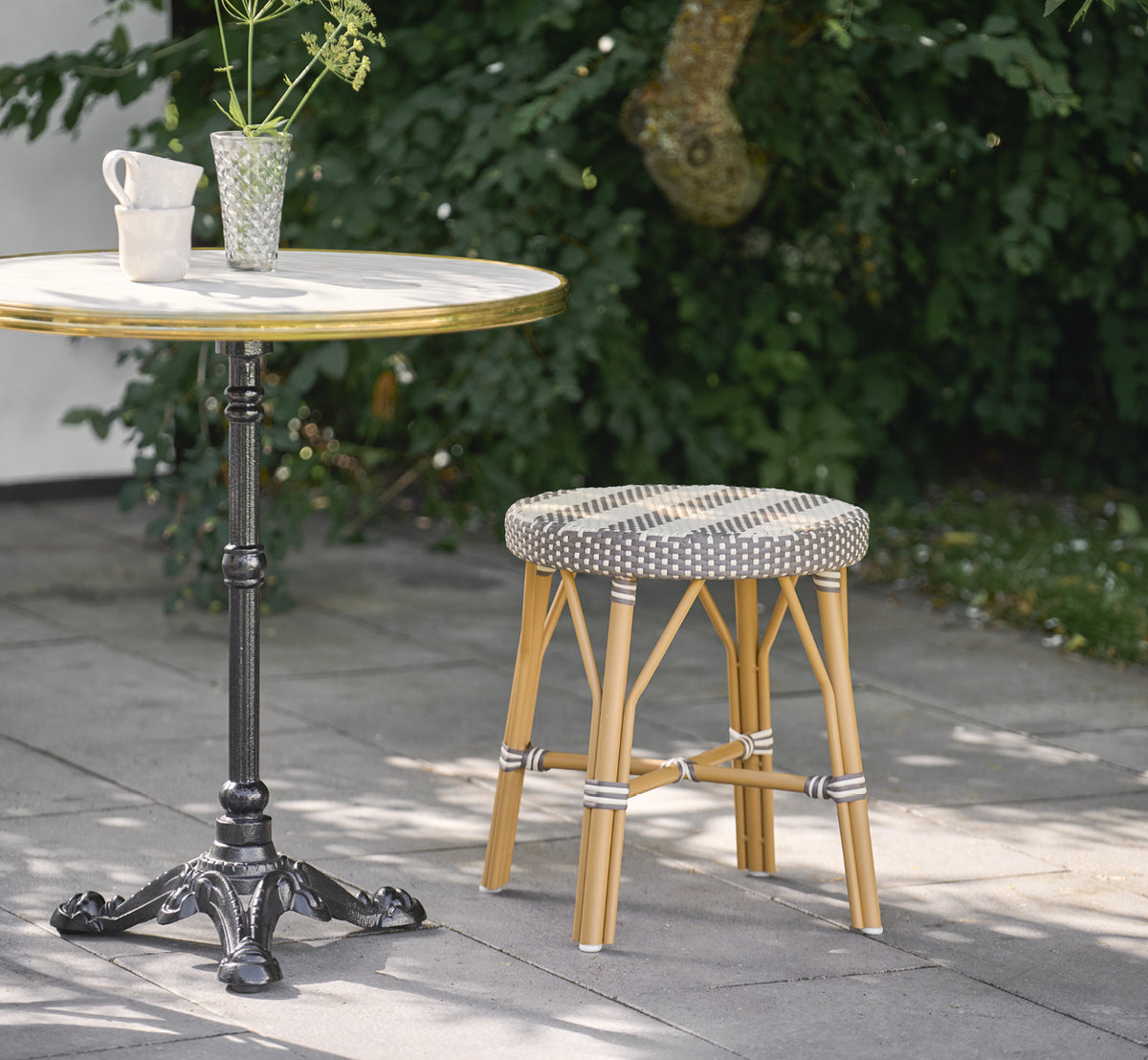 Dies ist ein Lifestyle-Bild von Simone Außen-Hocker in almond aluminium frame striped cappuccino ivory artfibre. In einem hellen Interieur gestylt.