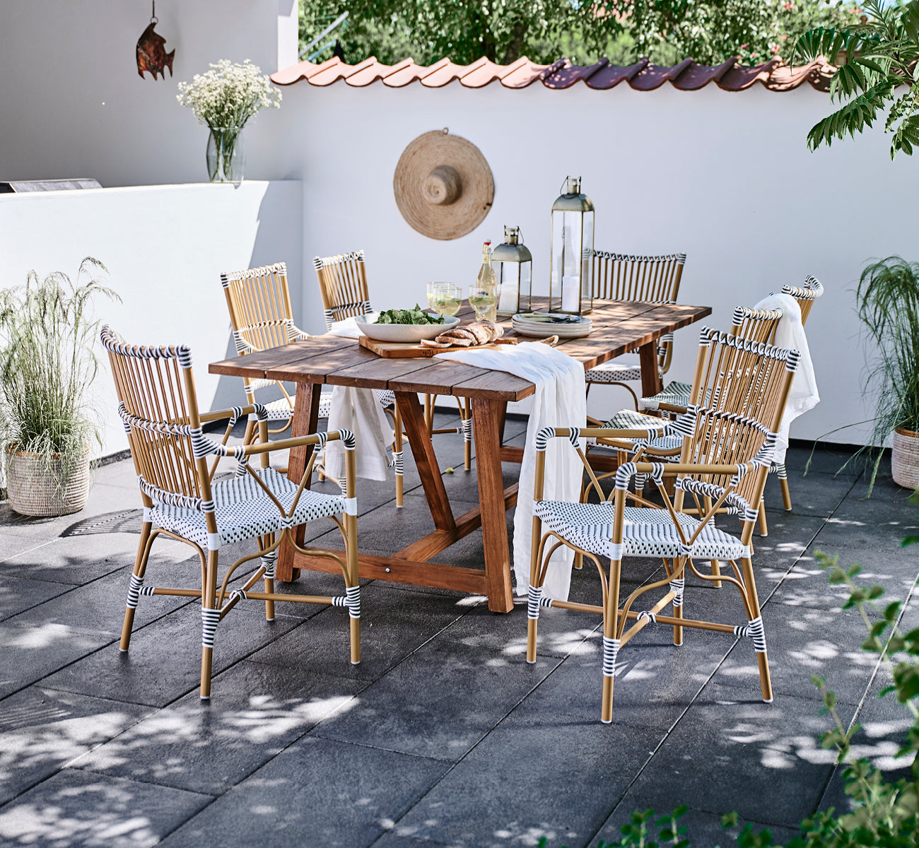 Dies ist ein Lifestyle-Bild von Monique Exterior Dining Armchair i white w cappuccino dot ArtFibre. Um einen Teaktisch auf einer Terrasse.