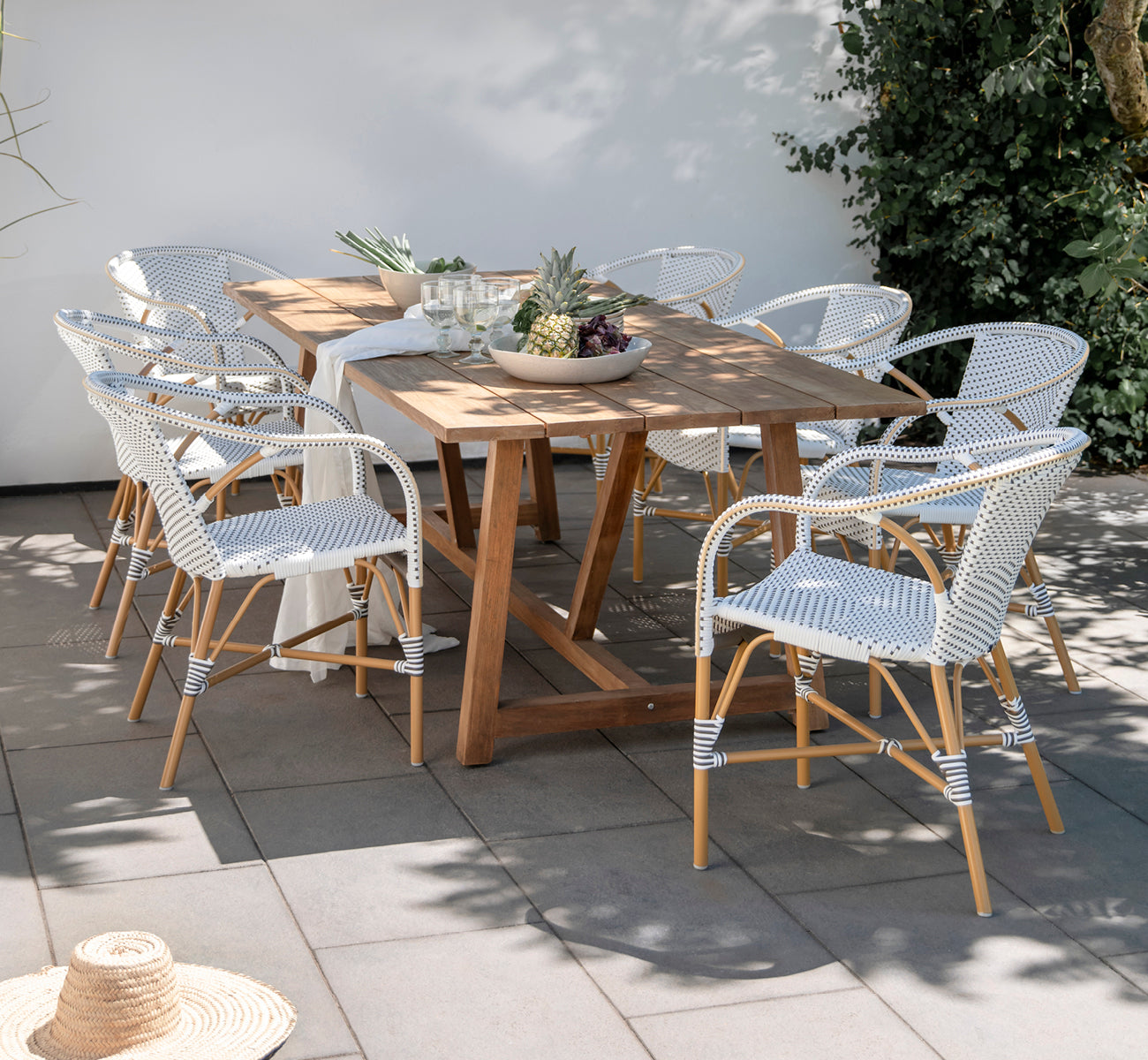 Dies ist ein Lifestyle-Bild von Madeleine Außen-Esszimmerstuhl in almond aluminium frame white w cappuccino dot ArtFibre. Gartenessen mit Teaktisch.