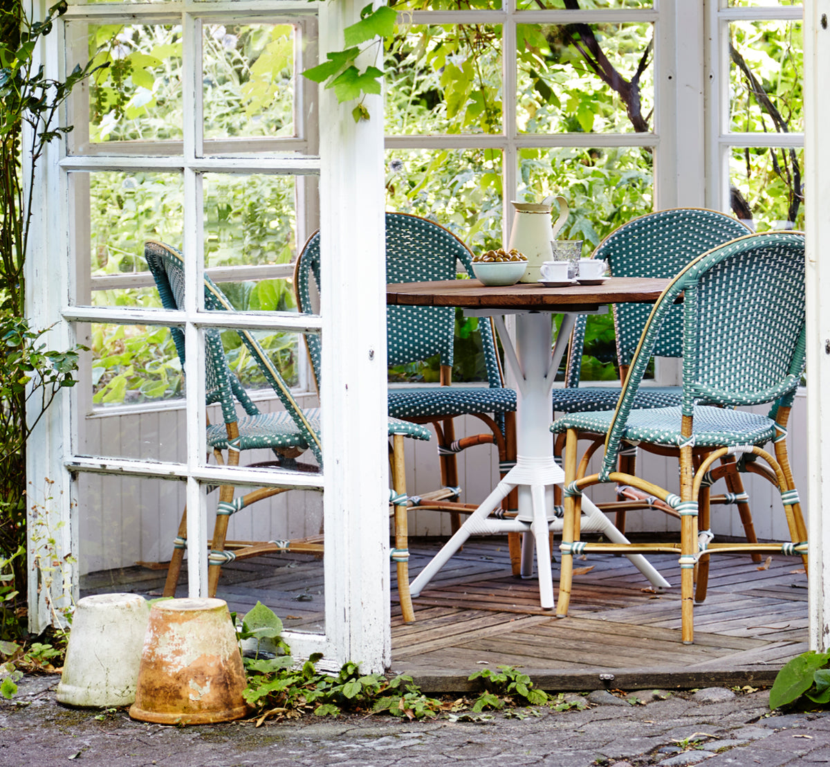 Dies ist ein Lifestyle-Bild von Sofie Esszimmerstuhl in salvie green w white dot artfibre skin on rattan frame. In einem hellen Interieur gestylt.