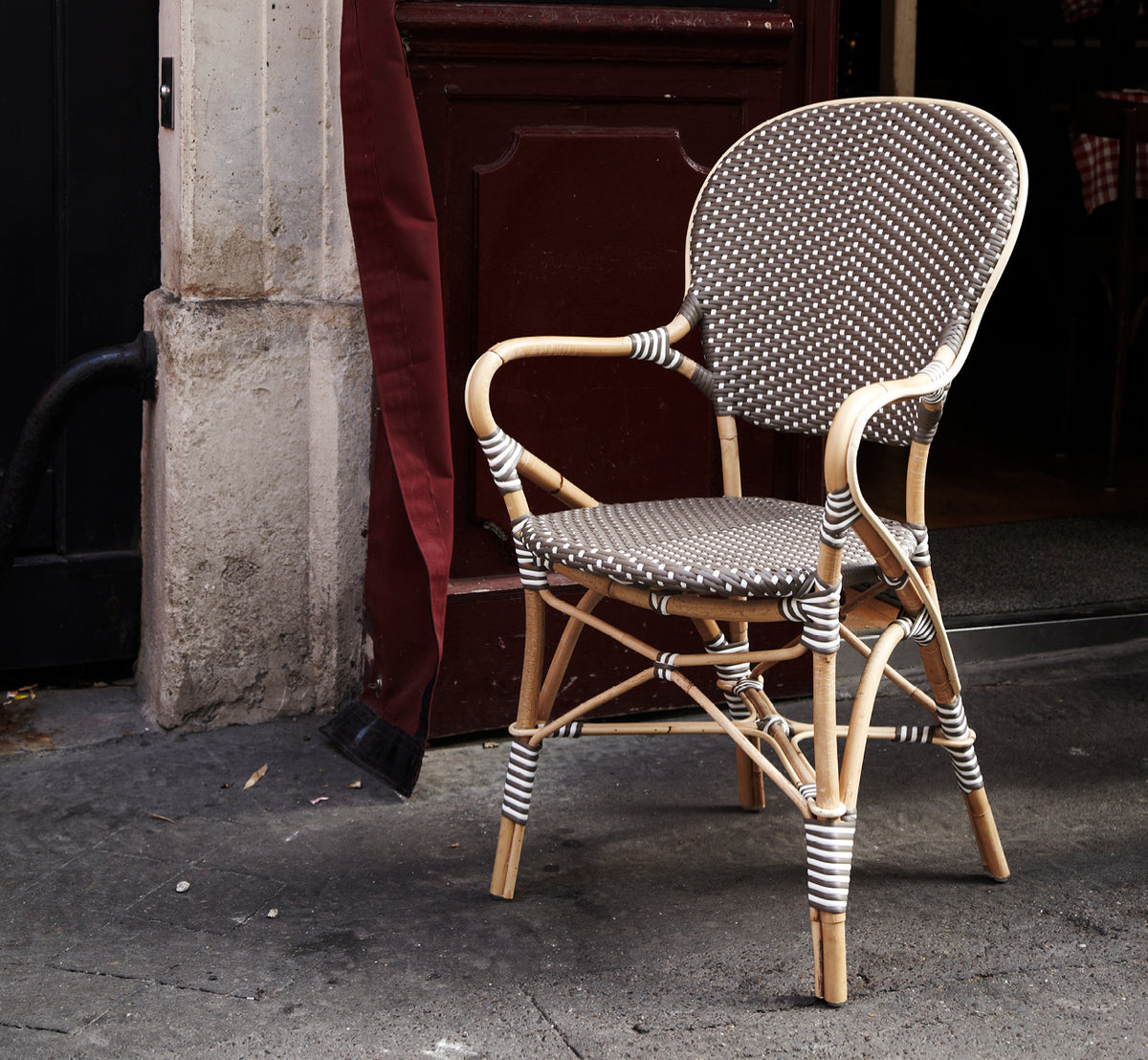 Dies ist ein Lifestyle-Bild von Isabell Esszimmer-Armlehnstuhl in cappuccino w white dot ArtFibre skin on rattan frame, in einem hellen Essbereich.