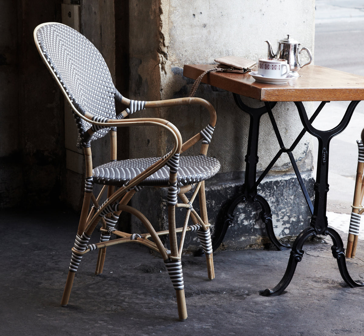 Dies ist ein Lifestyle-Bild von Isabell Esszimmer-Armlehnstuhl in cappuccino w white dot ArtFibre skin on rattan frame, in einem hellen Essbereich.