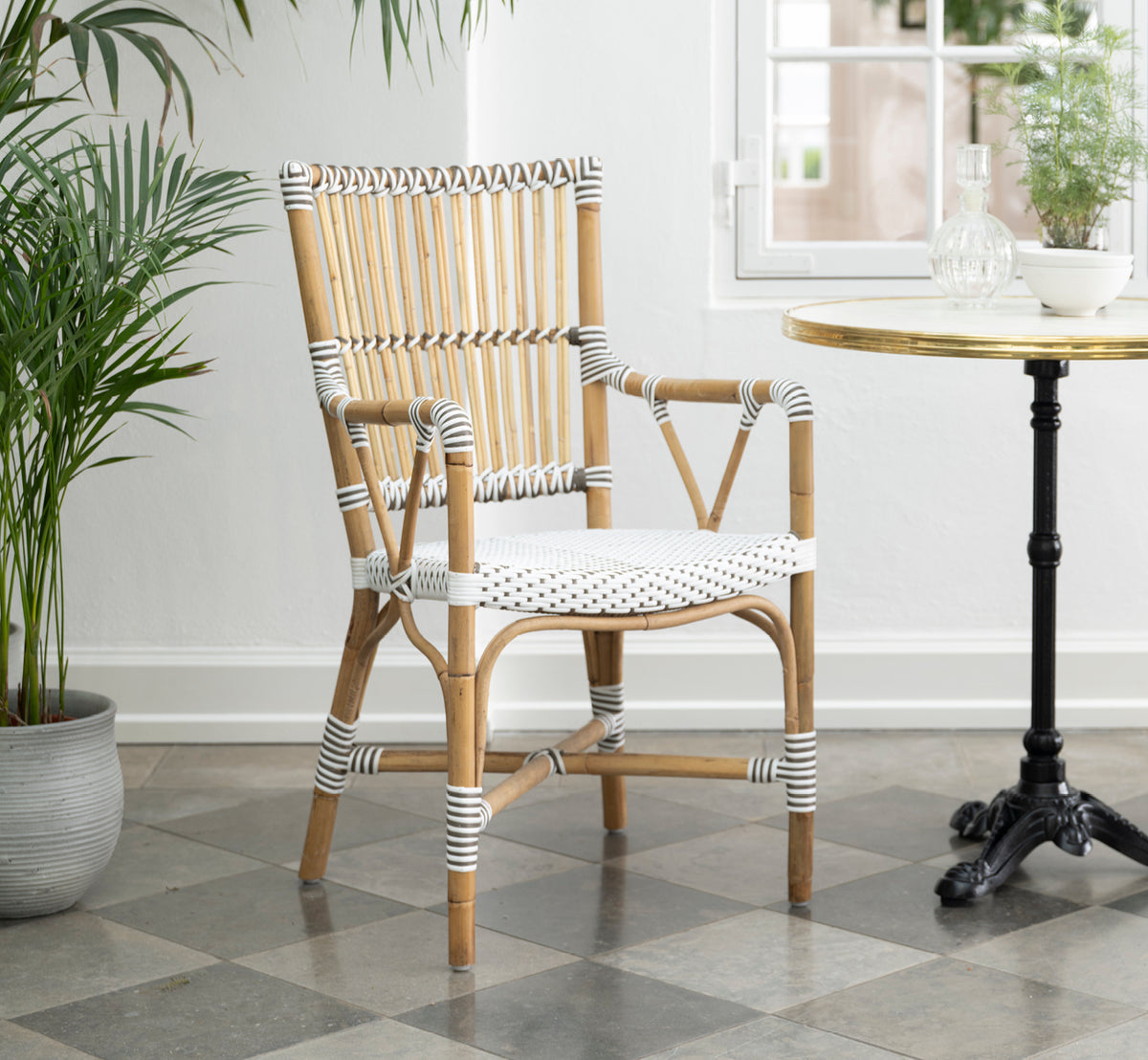 Dies ist ein Lifestyle-Bild von Monique Esszimmer-Armlehnstuhl in white w cappuccino dot artfibre skin on rattan frame. In einem hellen Interieur gestylt.