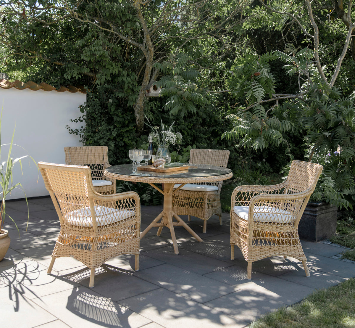 Dies ist ein Lifestyle-Bild von Marie Außen-Armlehnstuhl in natural artfibre aluminium. In einem hellen Interieur gestylt.