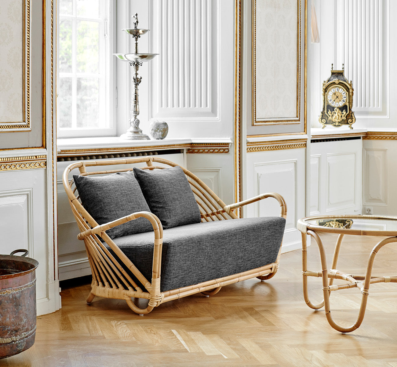 Dies ist ein Lifestyle-Bild von Charlottenborg Sofa in polished Natural Rattan, in einem eleganten klassischen Interieur mit aufwändigen goldenen.
