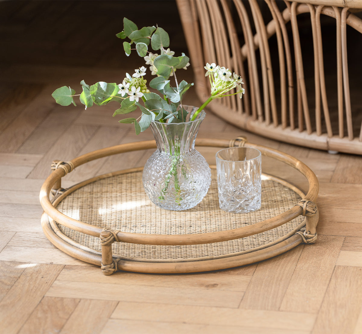 Dies ist ein Lifestyle-Bild von Andreas Tablett in natural Rattan, in einem hellen Interieur mit Fischgrätparkett.