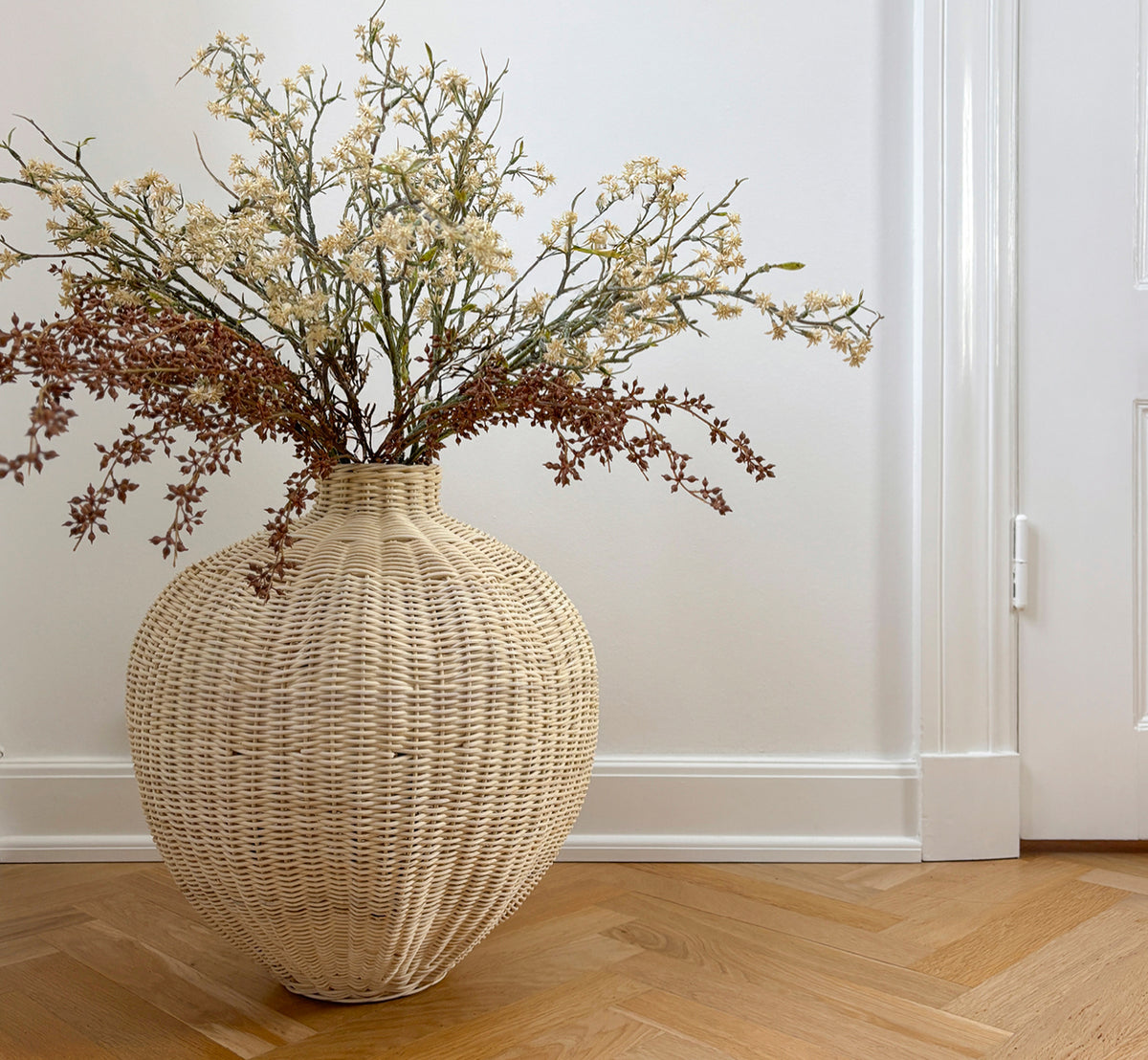 Dies ist ein Lifestyle-Bild von Flumen Korb in natural core weave iron frame, in einem hell-weißen Interieur mit Wandvertäfelung, dekoriert mit.