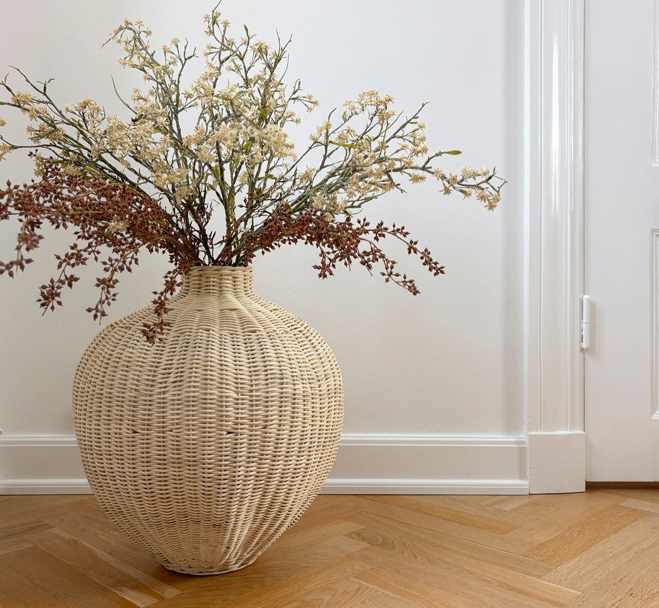 Dies ist ein Lifestyle-Bild von Flumen Korb in natural core weave iron frame, in einem hell-weißen Interieur mit Wandvertäfelung, dekoriert mit.