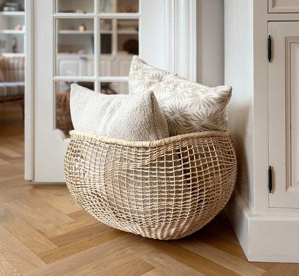 Dies ist ein Lifestyle-Bild von Folia Korb in natural core weave iron frame, in einem hell-weißen Interieur mit Wandvertäfelung, dekoriert mit.