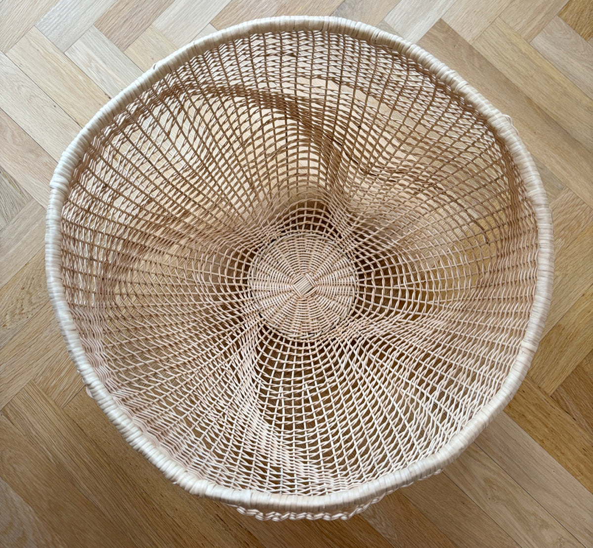 Dies ist ein Lifestyle-Bild von Folia Korb in natural core weave iron frame, in einem hell-weißen Interieur mit Wandvertäfelung, dekoriert mit.
