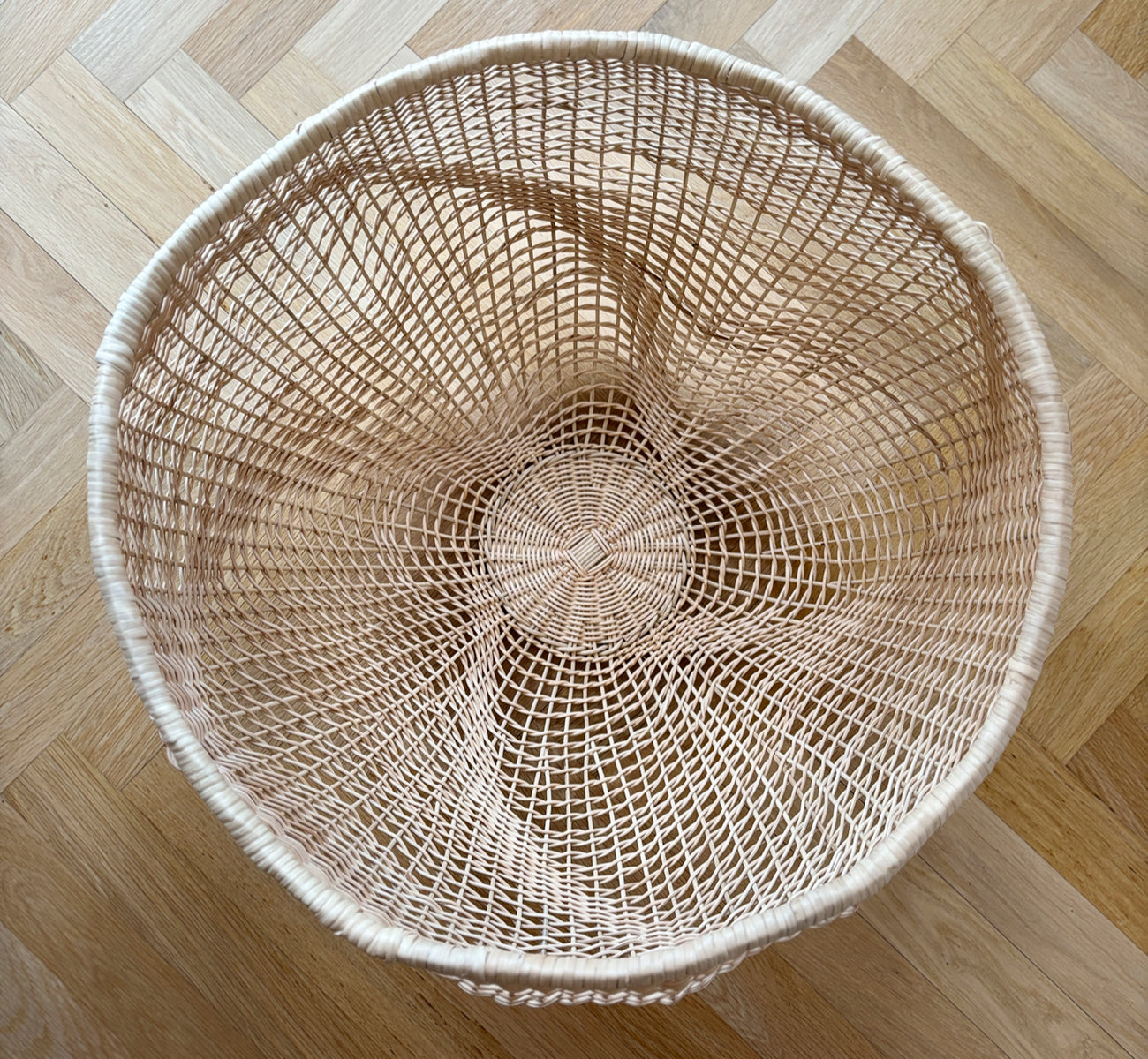 Dies ist ein Lifestyle-Bild von Folia Korb in natural core weave iron frame, in einem hell-weißen Interieur mit Wandvertäfelung, dekoriert mit.