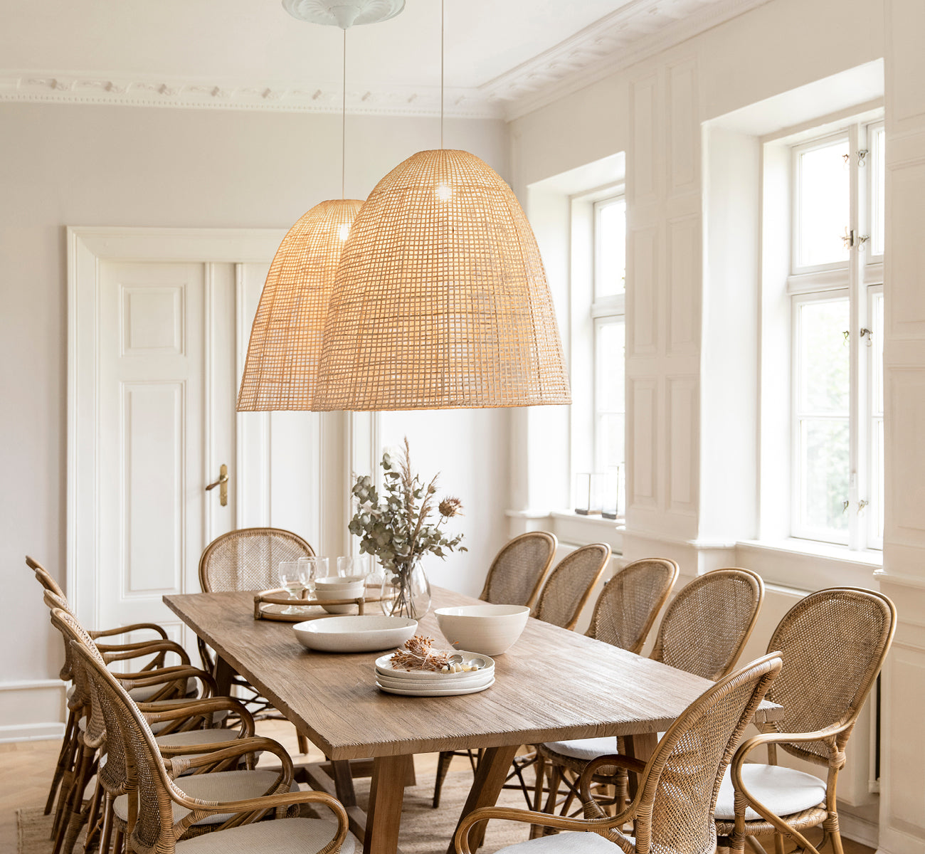 Dies ist ein Lifestyle-Bild von Showroom Lampenschirm in natural core weave artfibre & aluminium. Einen Esstisch mit Rattanstühlen darunter beleuchtend.