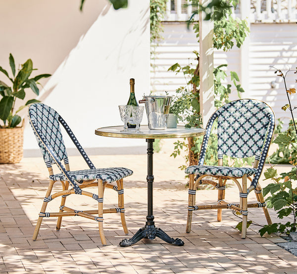 Dies ist ein Lifestyle-Bild von Lyon Cafétisch Versalite Marble Ø70 cm in cast iron. Sonnige Terrasse mit Bistrostühlen und einer Champagnerflasche.