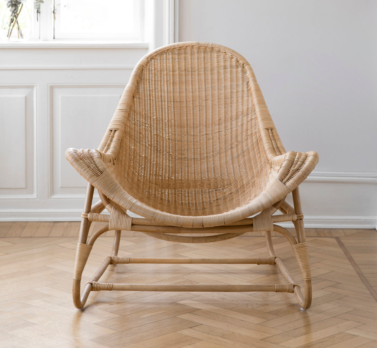 Dies ist ein Lifestyle-Bild von Pacifique Lounge-Sessel in natural core weave rattan frame. In einem hellen Interieur gestylt.