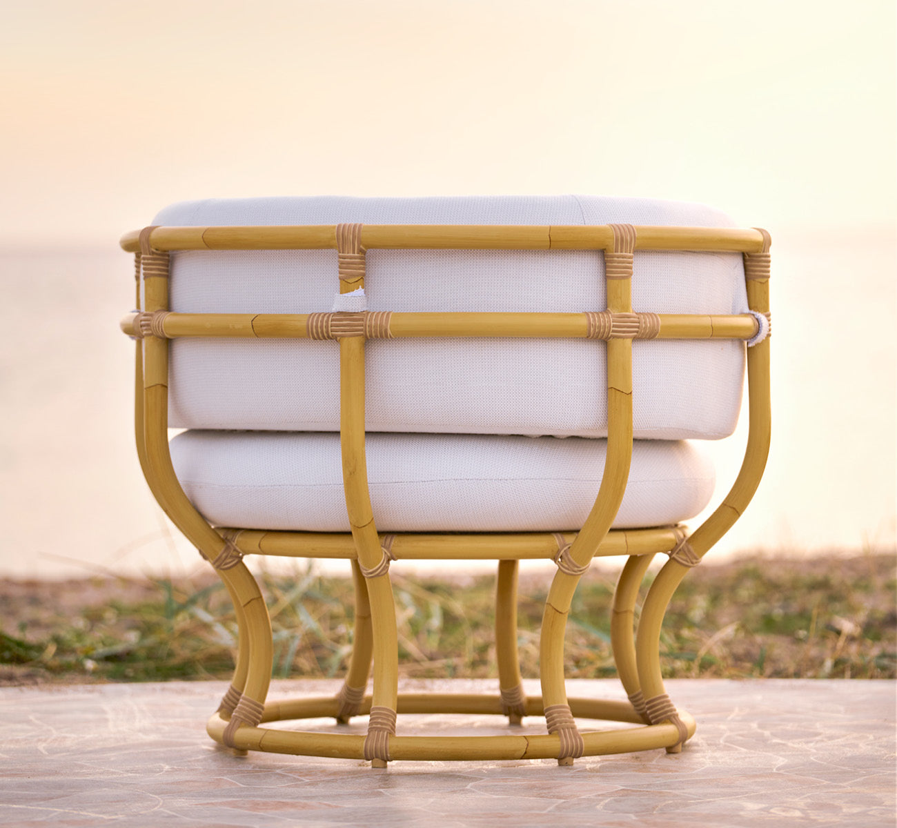Dies ist ein Lifestyle-Bild von Coco Außen-Lounge-Sessel in natural Aluminium ArtFibre, auf einer offenen Küstenterrasse bei Sonnenuntergang mit.
