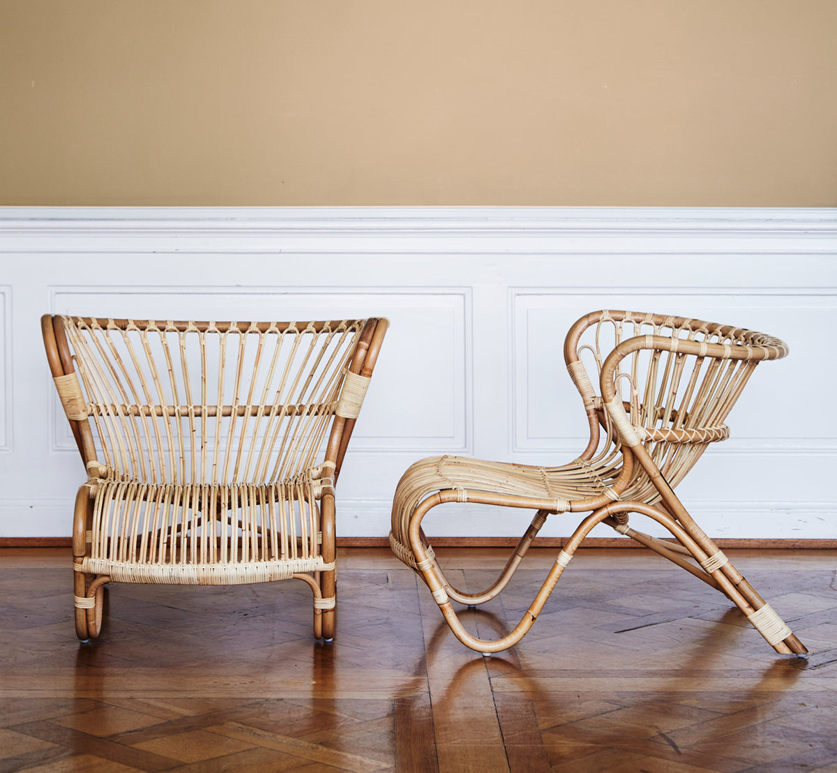 Dies ist ein Lifestyle-Bild von Fox Lounge-Sessel in polished Natural Rattan, in einem warmen Interieur mit ockerfarbener Wandvertäfelung und dunklem.