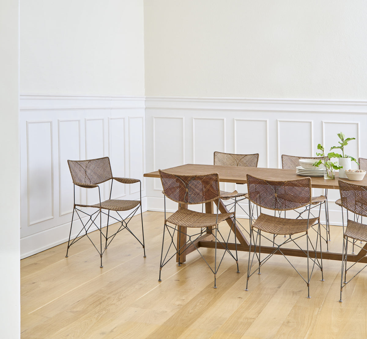 Dies ist ein Lifestyle-Bild von Rap Esszimmerstuhl in hazelnut rattan iron frame, in einem hellen Interieur mit weißen Wandpaneelen und.