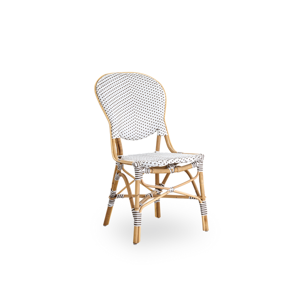 Seitenansicht des Isabell Essstuhls. Rattangestell mit Sitz- und Rückenfläche aus weißem ArtFibre mit braunen Punkten. Inspiriert vom Bistrodesign der 1950er Jahre.