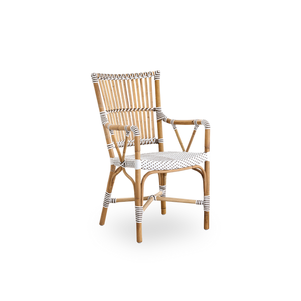 Seitenansicht des Monique Essstuhls mit Armlehnen. Rattanrahmen mit Sitz aus weißem ArtFibre mit braunen Punkten geflochten. Inspiriert vom Bistro-Design der 1950er Jahre.