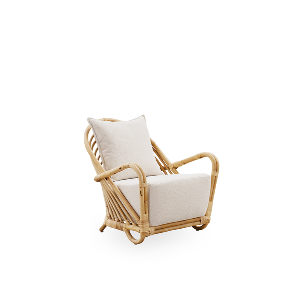 Seitenansicht des Charlottenborg Lounge-Stuhls aus poliertem Natur-Rattan, entworfen von Arne Jacobsen. Der Stuhl verfügt über eine gebogene Rückenlehne und in die Basis integrierte Armlehnen, handgefertigt aus hochwertigem indonesischem Rattan.
