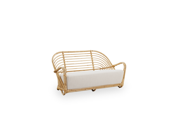 Seitenansicht des Charlottenborg 2-Sitzer-Sofas aus poliertem Natur-Rattan, entworfen von Arne Jacobsen. Das Sofa verfügt über eine gebogene Rückenlehne und in die Basis integrierte Armlehnen, handgefertigt aus hochwertigem indonesischem Rattan.