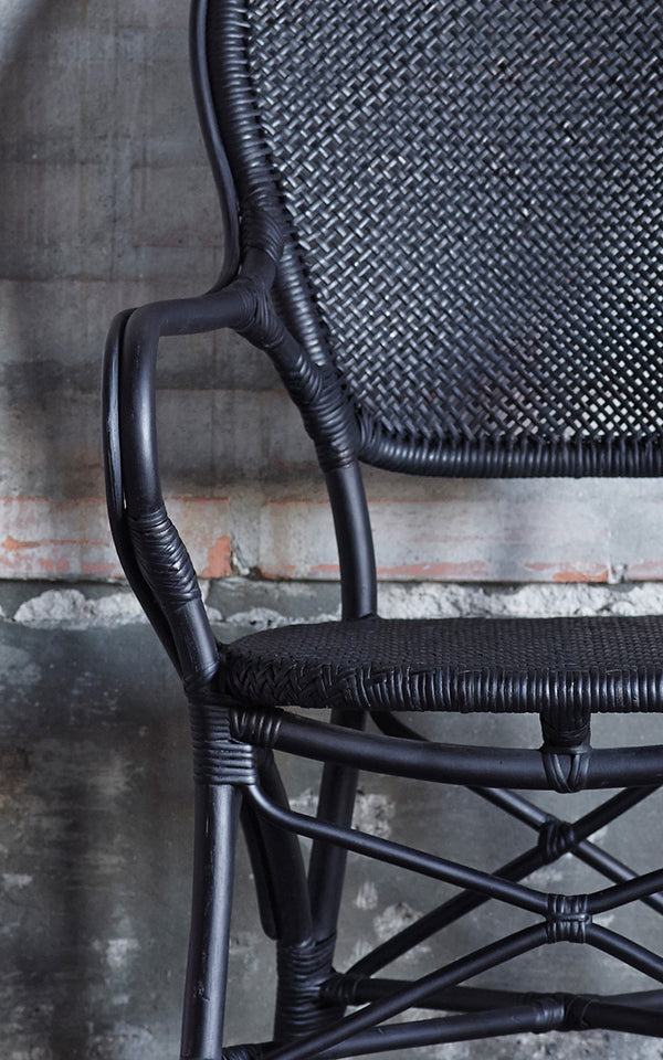 Dies ist ein Nahaufnahmebild von Rossini Armlehnstuhl in black rattan. Detail des komplett schwarzen Rattangeflechts und der gebogenen Armlehne.